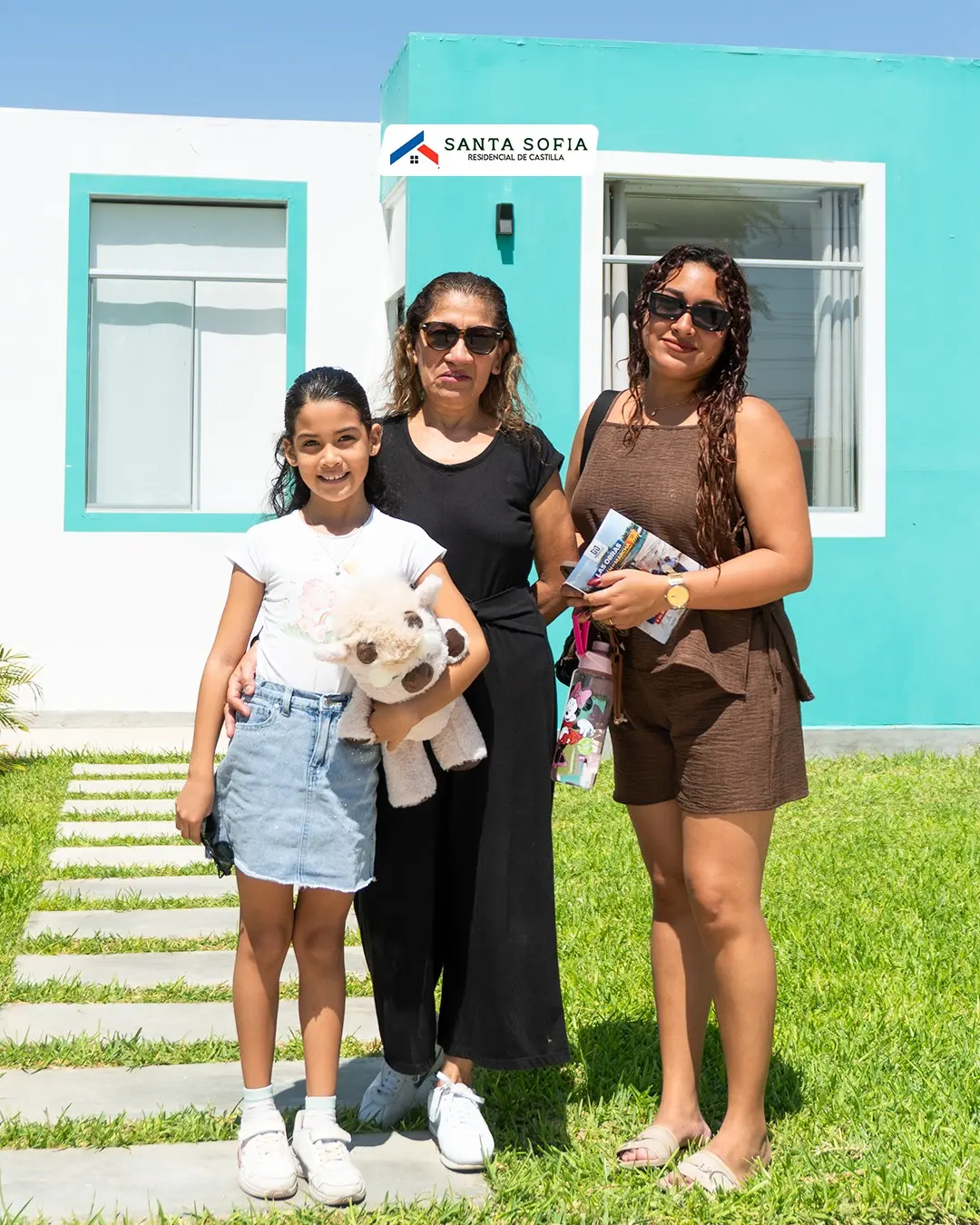 Familia posando frente a su nueva casa turquesa en Castilla, Piura
