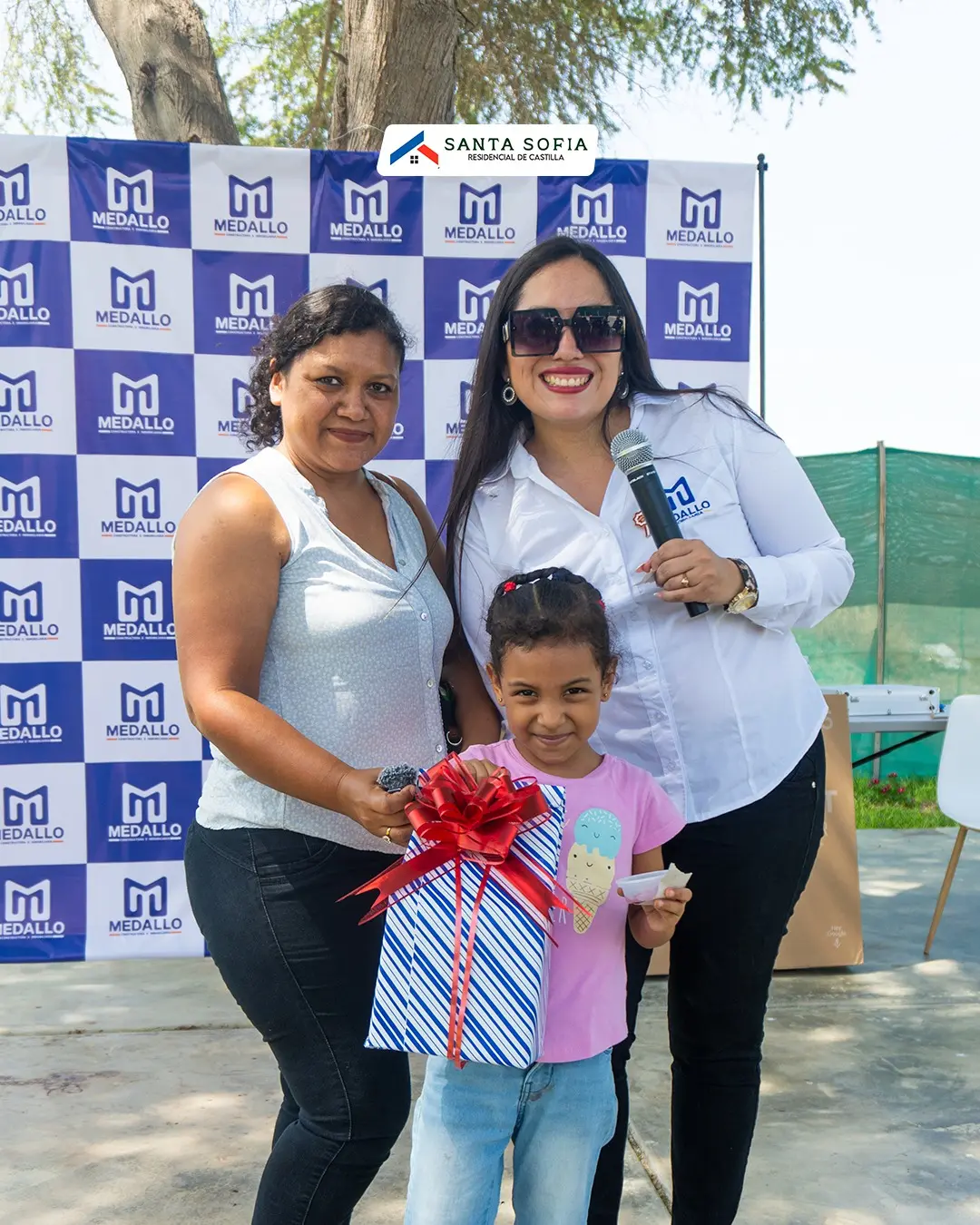 Familia celebrando su casa propia frente al panel de Inmobiliaria Medallo en Piura