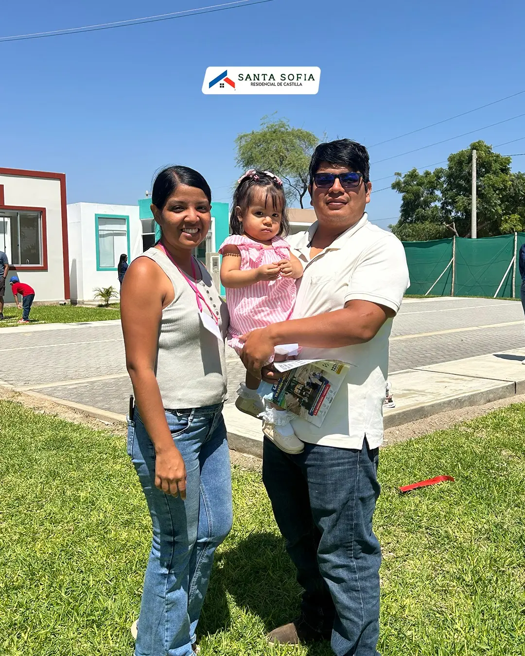 Familia con un niño pequeño frente a las casas de Inmobiliaria Medallo en Castilla, Piura